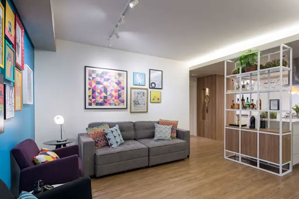 Decoração de uma sala em apartamentos studios usando uma estante para fazer a divisão entre a sala e a cozinha